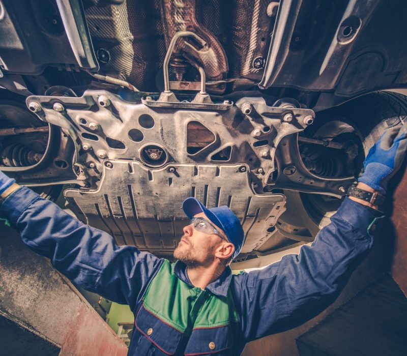 Auto Mechanic Under the Car Auto Mechanic Under the Car Trying to Fix the Problem. Vehicle Maintenance Concept Photo.